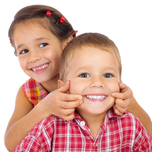 Two funny smiling little children, showing their teeth, isolated on white