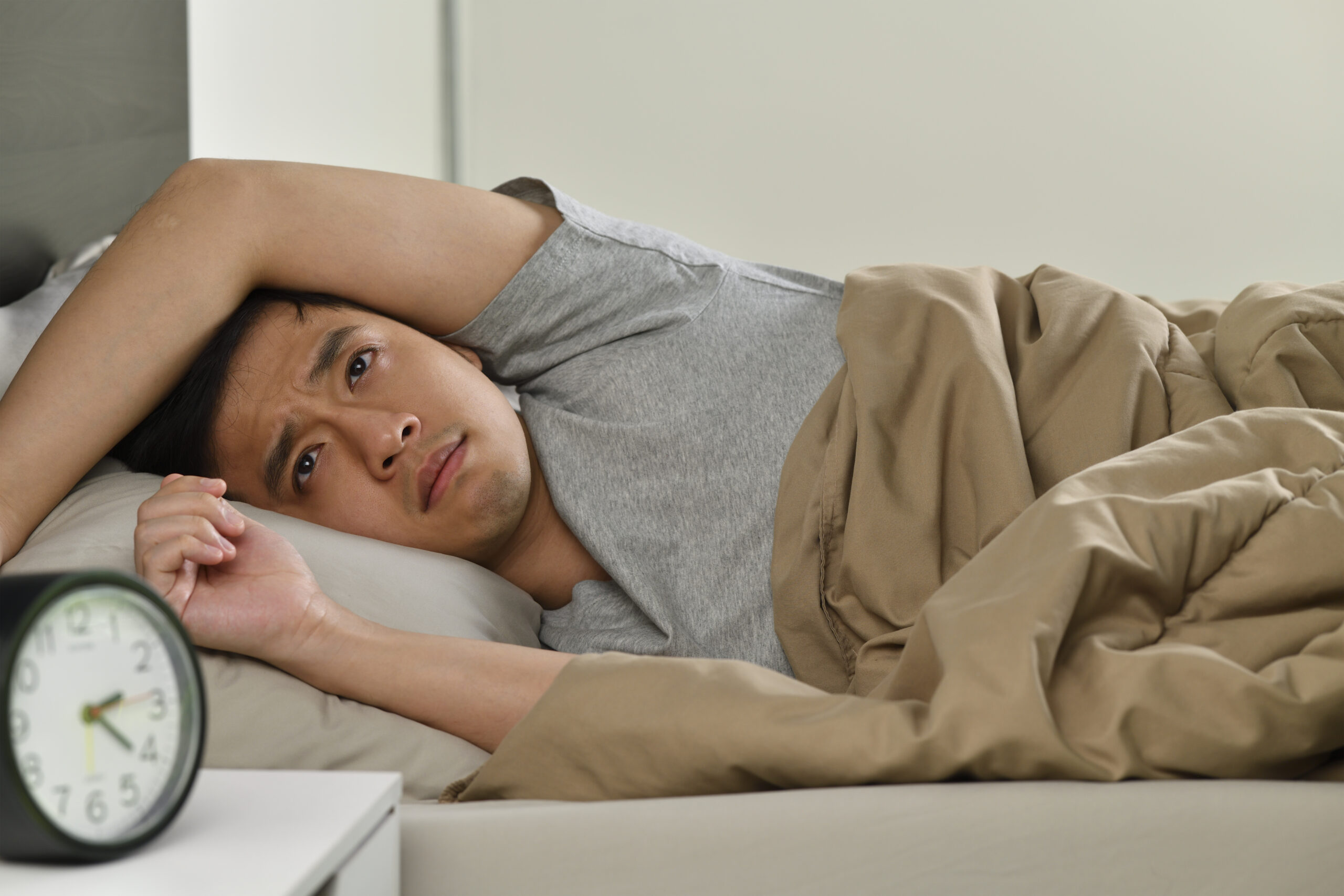 Depressed young Asian man lying in bed cannot sleep from insomnia Mouth breathing